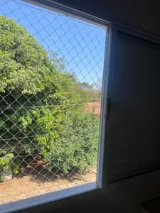 Rede de proteção branca instalada em janela de quarto com vista para área verde no bairro Mata do Jacinto em Campo Grande MS - UauTelas Bairro Mata do Jacinto MS