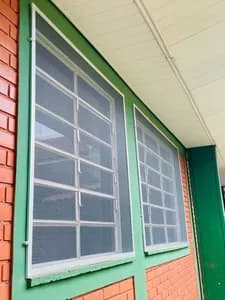 Conjunto de telas mosquiteiro instaladas em janelas sequenciais de fachada residencial. - UauTelas Terenos MS