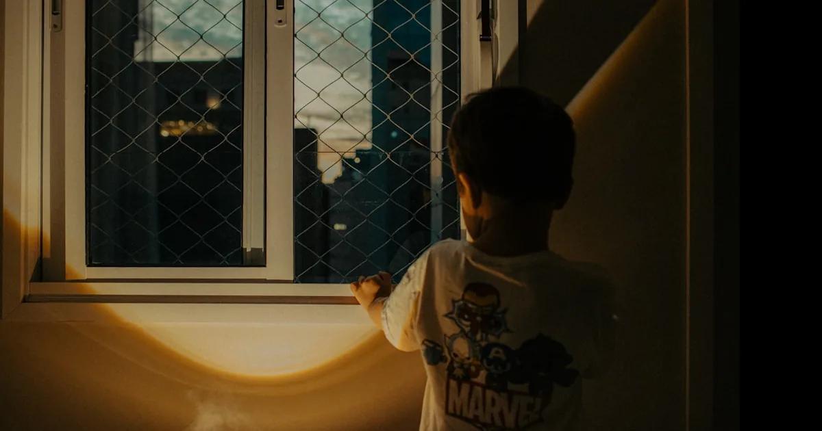 Criança perto de janela de apartamento — prevenção de queda