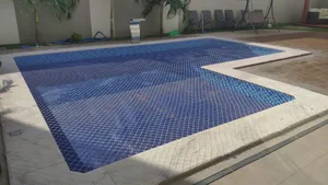 Piscina em formato L protegida com rede de proteção branca em área externa no bairro Centenário em Campo Grande MS