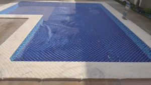 Rede de proteção branca instalada sobre piscina em formato L com borda de pedra no bairro Noroeste em Campo Grande MS
